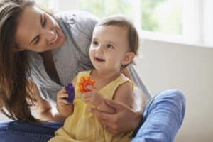 Shot of a cute baby girl sitting on the floor with her mom and playing with toys