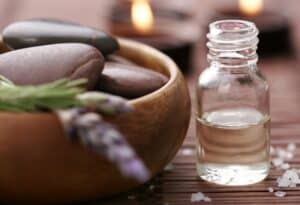 bottle of essential oil, massage stones,candles,lavander and bath-salt in a tight composition
